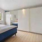 Schlafzimmer mit Bett, Kleiderschrank und Fenster mit Blick nach draußen.