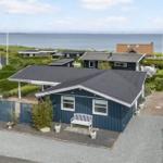 Blau gestrichenes Ferienhaus mit Garten und Blick aufs Meer.