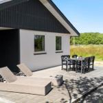 Terrasse mit Liegen und Tisch. Haus mit schwarzem Dach und weißen Wänden.