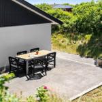 Terrasse mit Tisch und Stühlen neben einem Haus mit schwarzem Dach.