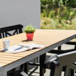 Helle Terrasse mit Tisch, Stühlen, Tasse und Zeitschrift. Ein kleiner Topf mit Pflanze.