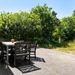 Terrasse mit Tisch und Stühlen, umgeben von Grün und Bäumen.