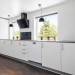 Moderne Küche mit weißen Schränken, Fenster und Küchengeräten.