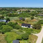 Aerial view of holiday homes among greenery with distant waterfront and industrial area.