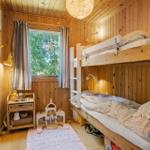 Ein Schlafzimmer mit Doppelstockbett, Holzwänden und einem Fenster mit Blick auf Bäume.