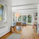 Wohnraum mit Holzboden, Tisch, Stühlen und Blick auf Garten.