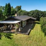Haus mit Terrasse, Grill und Fahrrad im grünen Garten.