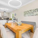 Dining area with wooden table and chairs, kitchen area in background.