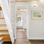 Staircase with wooden steps, wall art, and view into the bedroom.