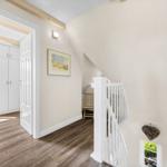Staircase with wooden steps, white railings, and view into bedroom.