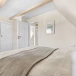 Bedroom with sloped ceiling, bed, wardrobe, and TV.