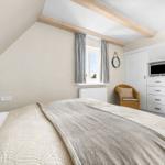 Bedroom with sloped ceiling, bed, wardrobe, and chair.