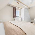 Bedroom with sloped ceiling, window, bed, and wardrobe.