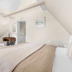 Bedroom with sloped ceiling, bed, desk, and wall picture.
