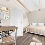 Bedroom with bed, desk, and mirror under wooden beam ceiling.
