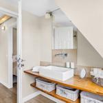 Bathroom with sink, mirror, and baskets. Door leads to bedroom.