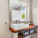 Sink with wooden vanity and mirror above the window