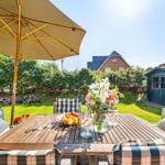 Wooden table with seating under an umbrella in the garden.