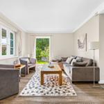 Living room with sofa, armchairs, table, and view of the garden.