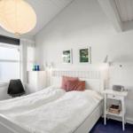 Schlafzimmer mit weißem Bett, Fenster und Deckenleuchte.