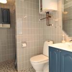 Badezimmer mit Toilette, Waschbecken und Dusche. Wandfliesen und blauer Schrank.