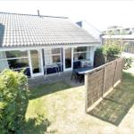 Haus mit Garten, Terrasse und Sitzgelegenheiten. Holzzaun und Pflanzen umgeben den Außenbereich.