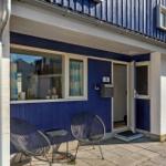 Blau gestrichene Fassade mit Terrasse, zwei Stühlen und Tisch vor der Tür.
