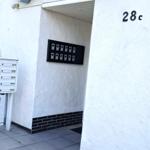 Eingangsbereich mit Hausnummer 28c und Briefkasten. Weiße Wand, graue Fliesen und Pflanzen.
