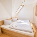 Schlafzimmer mit Doppelbett, Schrank und Nachttisch. Dachfenster und Holzmöbel.