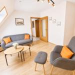 Wohnzimmer mit grauem Sofa und Sessel, Holzboden und Dachfenster.