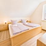 Zimmer mit Doppelbett, Nachttischen und Fenster mit Blick nach draußen.