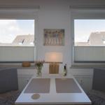 Dining area with table, two chairs, and windows with blinds.