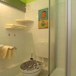 Bathroom with shower, toilet, sink, and mirror. Wall art and towels are present.