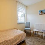 Ein Schlafzimmer mit Bett, Stuhl und Bild an der Wand.