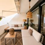 Terrasse mit Sitzgelegenheiten, Sonnenschutz und Hängelampe.