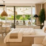 Schlafzimmer mit Bett, Tisch, Stühlen und Blick auf Balkon mit Garten.
