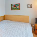 Ein Schlafzimmer mit einem Bett, Wandbildern und einem Holzschrank mit Stereoanlage.