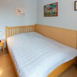 Schlafzimmer mit Holzbett, Nachttisch und Wandbildern