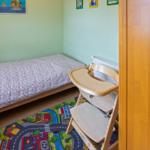 Ein Kinderzimmer mit einem Bett und einem Hochstuhl auf einem Spielteppich.