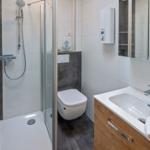 Badezimmer mit Dusche, Toilette und Waschbecken mit Spiegel.