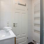 Badezimmer mit Waschbecken, Spiegelschrank und Duschbereich mit Heizkörper.