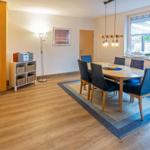 Esszimmer mit Holztisch, blauen Stühlen und Fensterblick auf Garten.