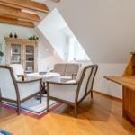Wohnzimmer mit Sitzgruppe, Schreibtisch und Treppe. Holzdecke und Parkettboden.