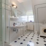 Badezimmer mit Dusche, Waschbecken, Waschmaschine und Fenster