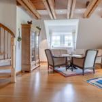 Eingangsbereich mit Holztreppe, Wohnzimmer mit Sitzgruppe und Bücherregal.