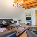 Wohnzimmer mit Ledersofa, Holzdecke und Fernseher.