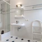Badezimmer mit Dusche, Waschbecken und Handtuchständern.