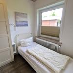 Ein Schlafzimmer mit Bett, Fenster und Wandbild. Holzfußboden und weißer Schrank.
