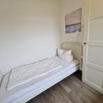 Ein Schlafzimmer mit weißem Bett, Wandbild und Schrank.