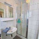 Badezimmer mit Dusche, Waschbecken und Spiegel an der Wand.